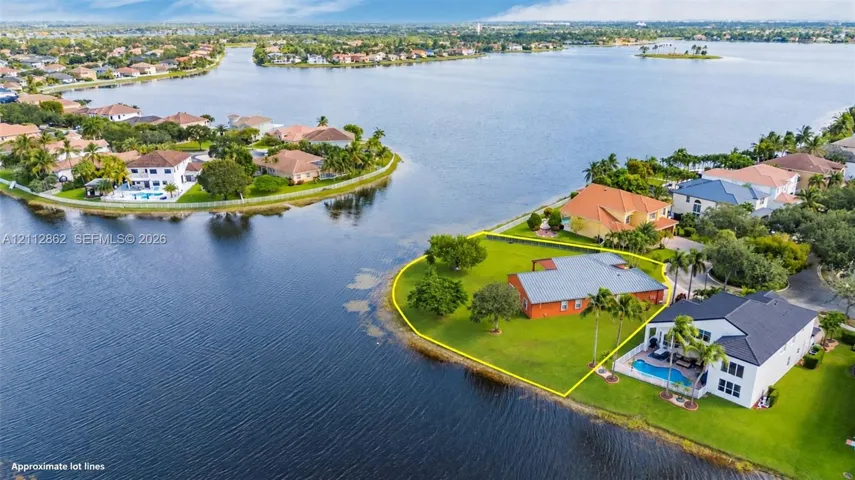 Waterfront residential parcel featuring extensive shoreline, mature trees, and sprawling lawn areas