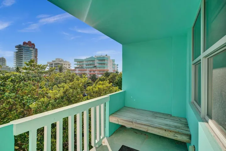 Private balcony featuring a built-in wooden bench, painted concrete surfaces, and metal railings