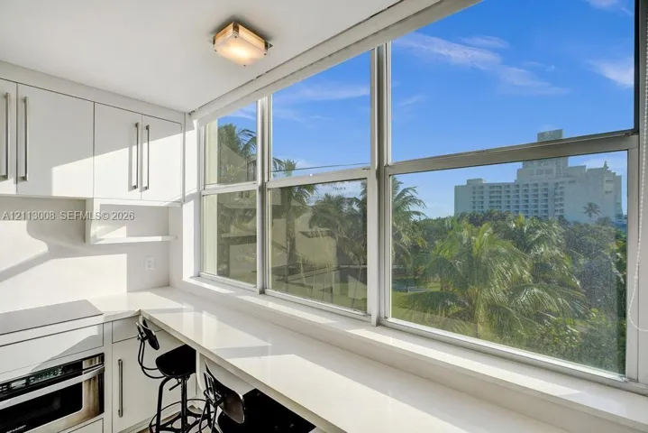 White cabinetry, expansive window wall, integrated stone-surface countertop, and flush-mount ceiling lighting