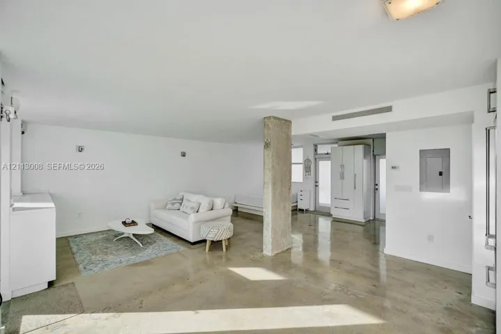 Open-concept interior featuring polished concrete flooring, an exposed structural concrete column, recessed lighting, and built-in white cabinetry