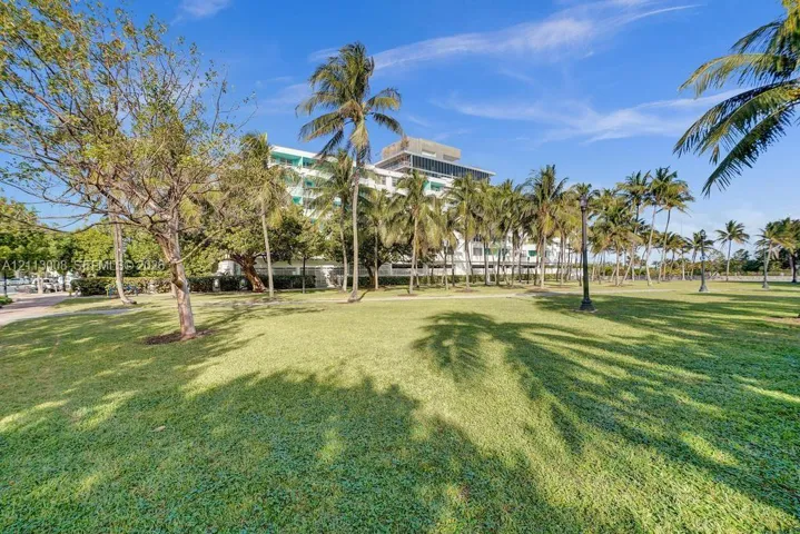 Expansive grounds featuring a manicured lawn, mature palm trees, and structural lighting