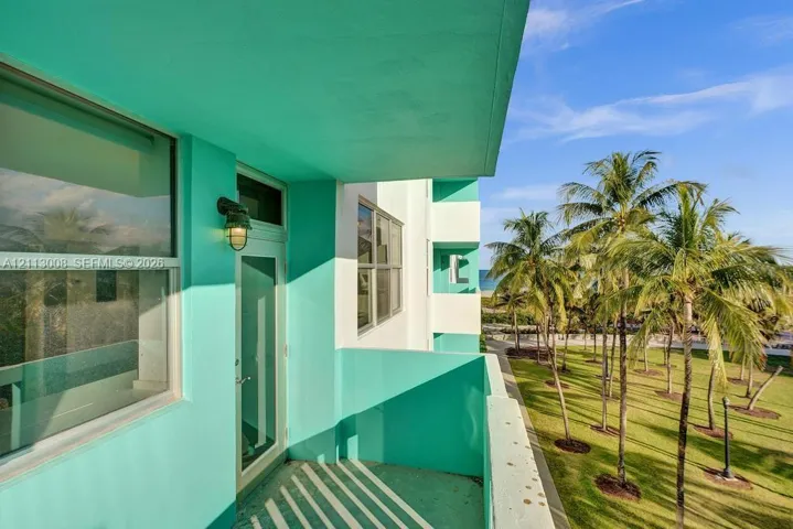 Private balcony featuring a solid partition wall, exterior light fixture, and glass-paneled entry door