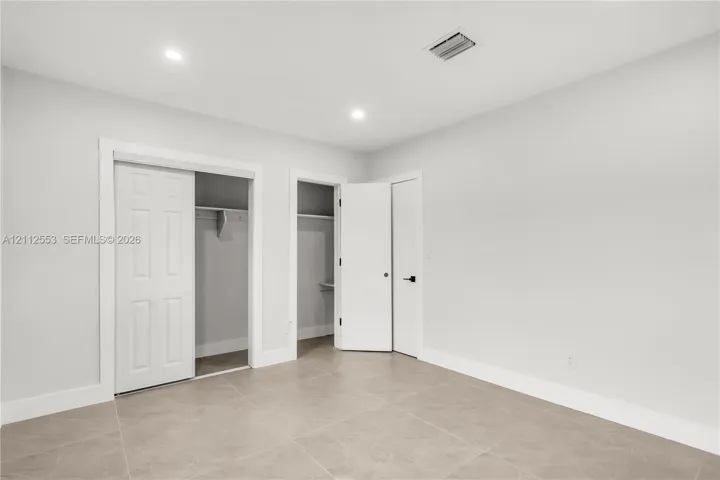 Neutral-toned tile flooring, recessed ceiling lighting, two reach-in closets, and solid-core doors with matte black hardware