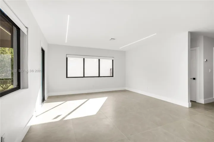 Neutral-toned tile flooring, recessed linear LED ceiling lighting, and black-framed windows