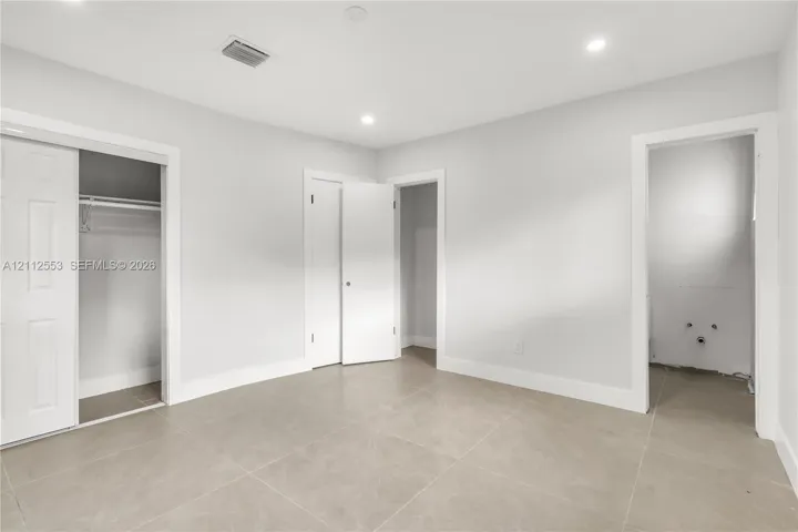 Neutral-toned ceramic tile flooring, recessed ceiling lighting, and multiple interior closets with white paneled doors