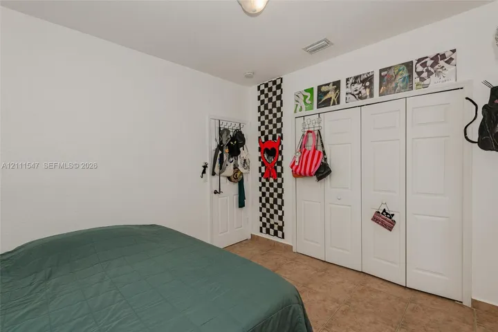 Interior space featuring neutral wall paint, tile flooring, and a multi-panel closet with white doors