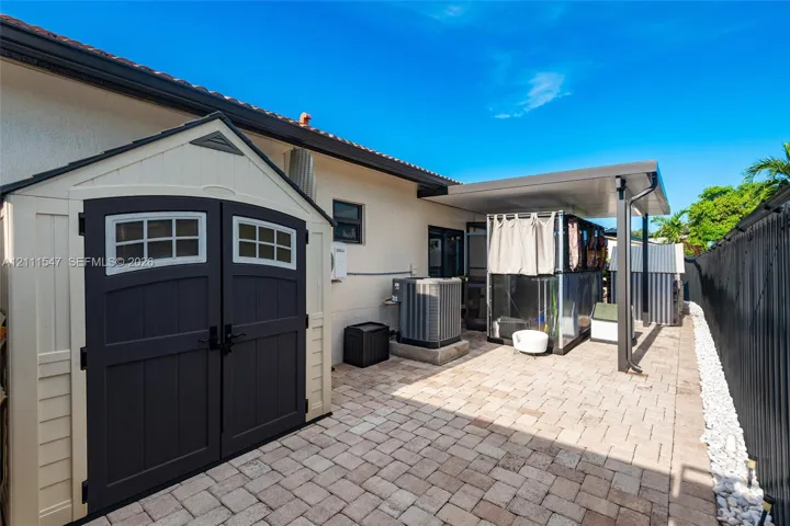 Side yard featuring paver hardscaping, a covered patio area, and a storage shed