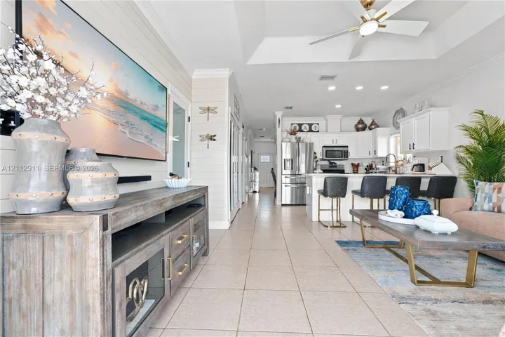 Open-concept floor plan featuring a trey ceiling, tile flooring, shiplap wall accents, recessed lighting, and a kitchen island with built-in cabinetry