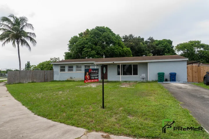 Single-story residence with a stucco exterior, a horizontal-plank wood fence, an asphalt driveway, and mature landscaping