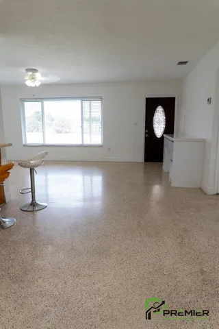 Terrazzo flooring, large multi-pane windows, dark-stained entry door with decorative glass insert, and built-in white cabinetry