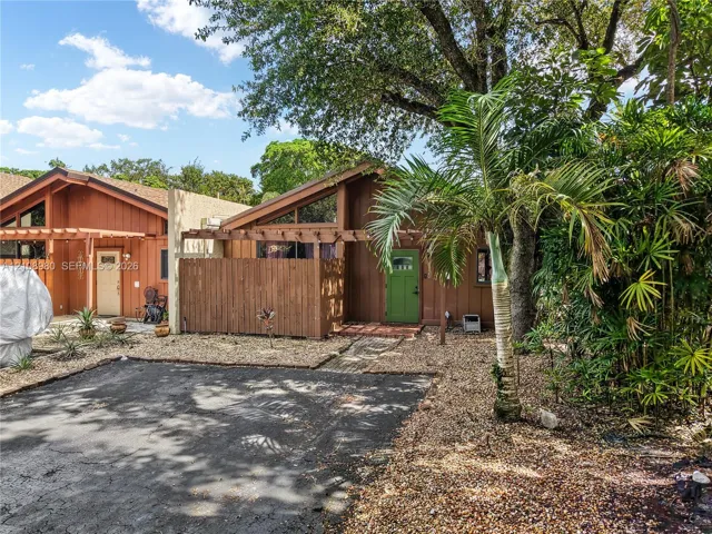 Exterior featuring a wood-sided facade, pitched roofline with triangular clerestory windows, attached pergola, and gravel landscaping