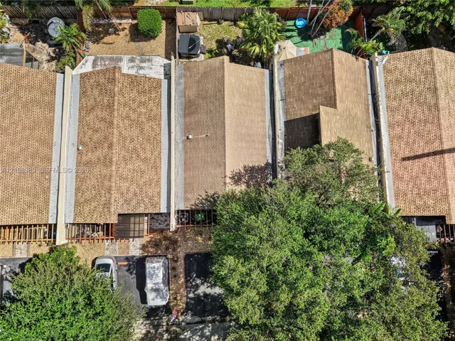 Aerial perspective featuring asphalt shingle roofing, paved surface parking, and mature canopy trees