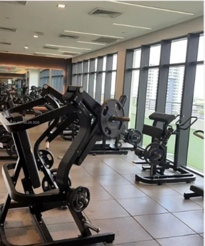 Fitness facility featuring expansive floor-to-ceiling windows, large-format tile flooring, recessed linear lighting, and integrated wall-to-wall mirrors