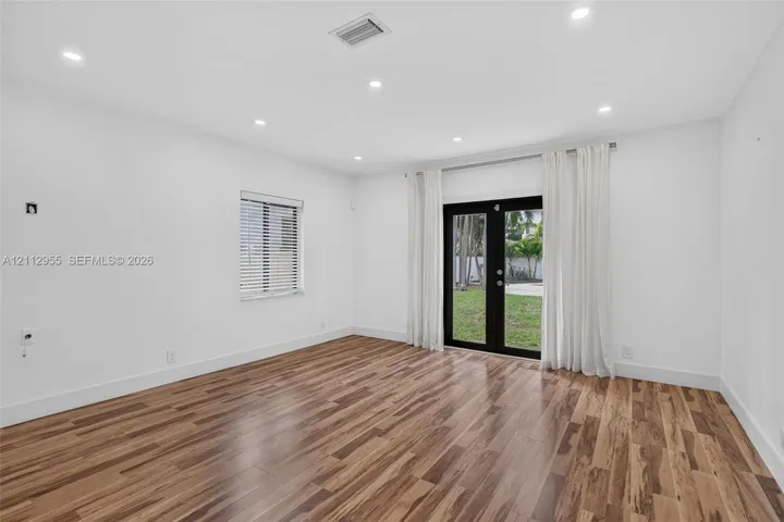 Interior space featuring wood-finish flooring, recessed lighting, and black-framed double glass doors providing an exterior perspective