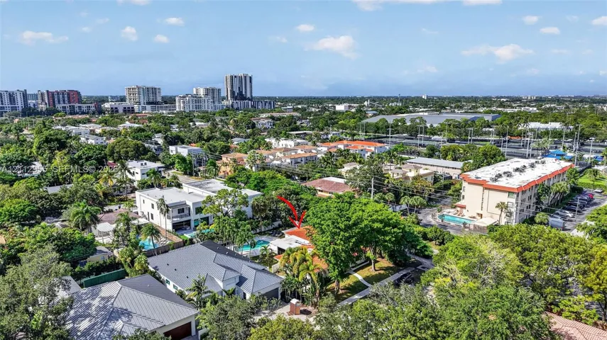 Aerial perspective of a property featuring a swimming pool, mature canopy trees, and a low-pitch roofline within a dense residential setting