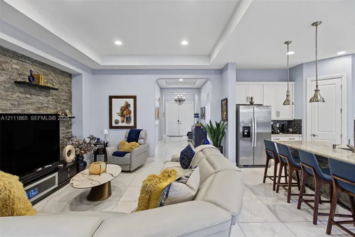 Living space featuring a stone accent wall & recessed tray ceiling.