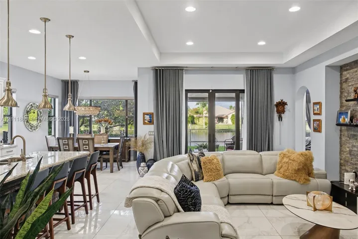 Broad view of open-concept floor plan featuring polished tile flooring & tray ceilings with recessed​​‌​​​​‌​​‌‌​‌‌​​​‌‌​‌​‌​‌​​​‌​​ lighting.