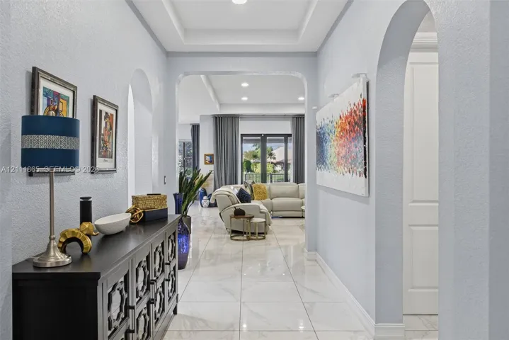 Entryway featuring large-format tile flooring, recessed tray ceiling, and prominent arched architectural openings