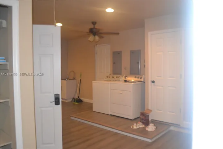 Utility area featuring wood-finish flooring, a raised platform for laundry appliances, a built-in sink, and multi-panel interior doors