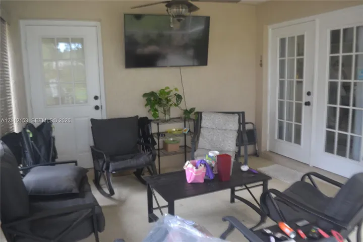 Covered patio featuring a neutral concrete floor, two glass-paned doors, and a ceiling fan