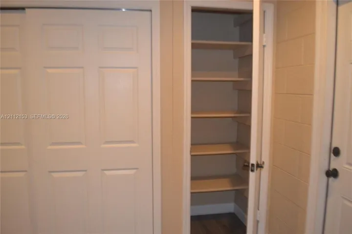 Built-in storage closet with six shelves, six-panel sliding door, and neutral-finish walls