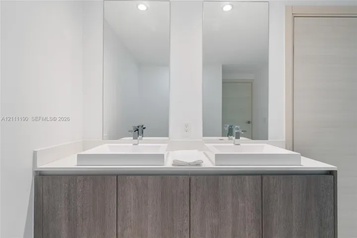 Dual-sink vanity featuring a solid surface countertop, rectangular vessel sinks, chrome fixtures, and full-height wall mirrors