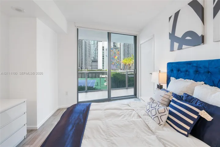 Floor-to-ceiling glass sliding door, wood-finish flooring, and recessed ceiling lighting, with access to a balcony featuring metal railing