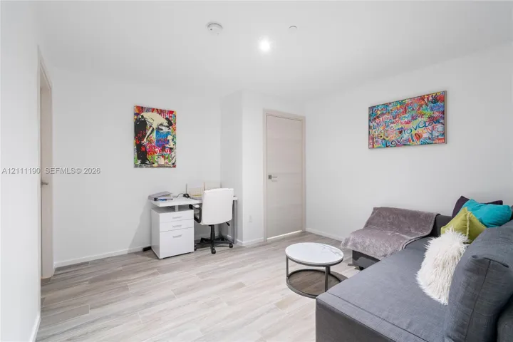 Neutral-toned interior space featuring wood-finish flooring and solid-core interior doors with matte-finish hardware
