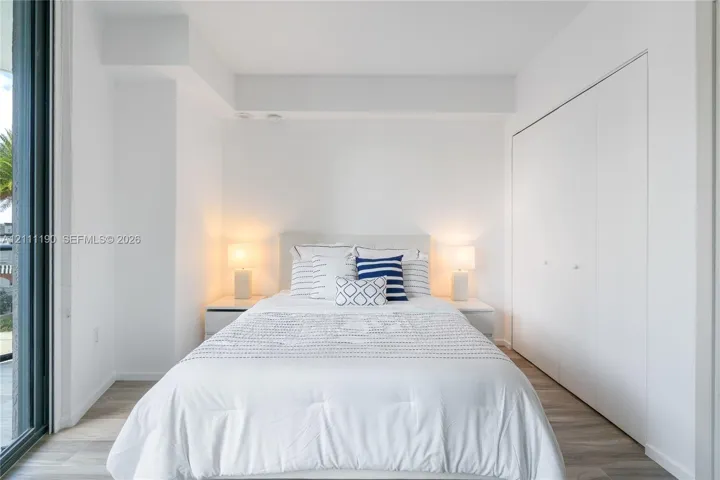 Wood-finish flooring, full-height sliding glass door, and built-in closet with white panel doors
