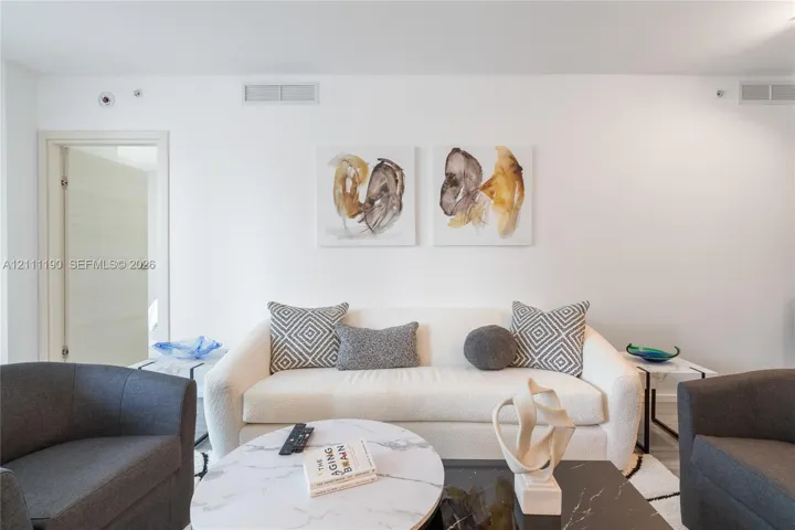 Neutral interior space featuring high ceilings, a flat-panel interior door with brushed metal hardware, and minimalist light-toned wall finishes