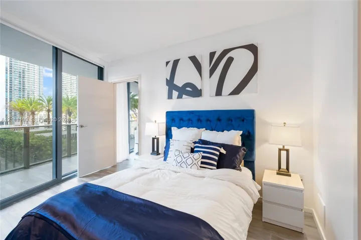 Floor-to-ceiling glass sliding doors, wood-finish flooring, and access to a private balcony