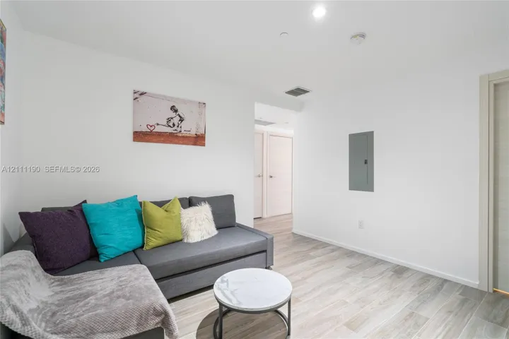Neutral interior space featuring wood-finish flooring, smooth white wall finishes, and light-toned interior doors