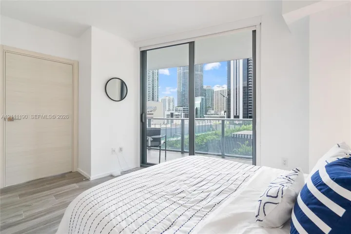 Floor-to-ceiling sliding glass door, wood-finish flooring, and balcony access with metal railing