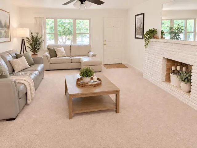 Living area featuring a floor-to-ceiling painted brick fireplace, wall-to-wall carpeting, multiple windows, and a ceiling-mounted light fixture