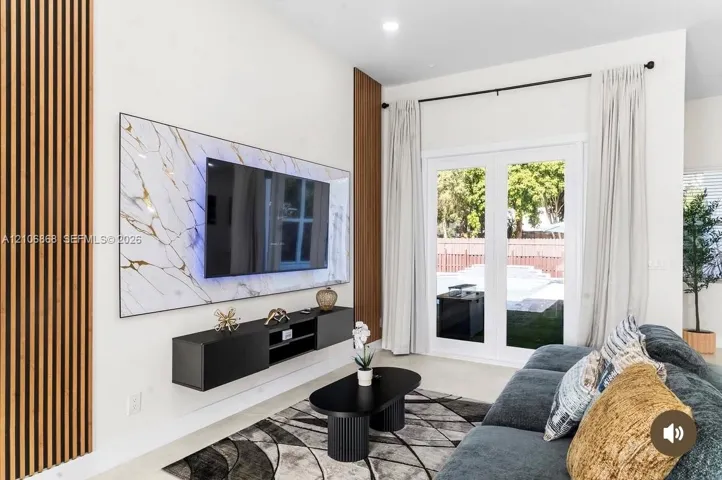 Living area featuring vertical slat wood wall paneling, a large stone-finish media wall, and a floating black console