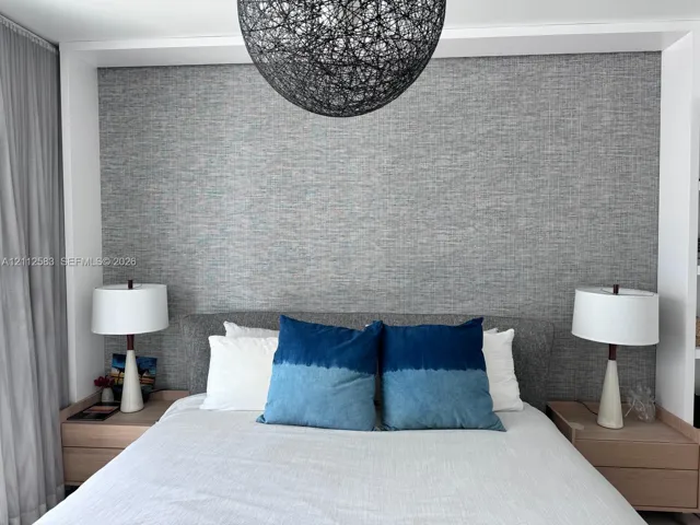 Textured gray wall accent, recessed built-in wood-finish nightstands, and spherical overhead pendant light​​‌​​​​‌​​‌‌​‌‌​​​‌‌​‌​‌​‌​​​‌​​ fixture