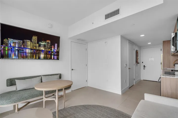 Neutral tone interior featuring large-format tile flooring, flat-panel wood-finish cabinetry, and recessed lighting