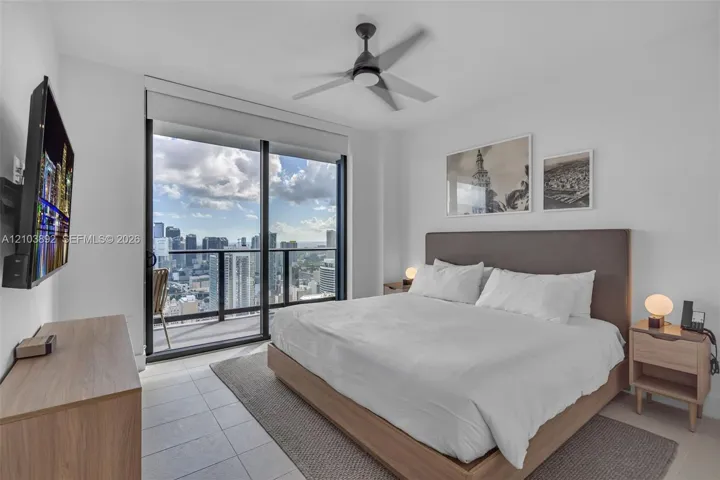 Floor-to-ceiling sliding glass door, private balcony with metal railing, tile flooring, and ceiling fan