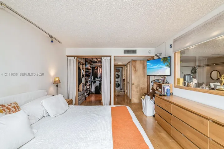 Bedroom featuring wood-finish flooring, built-in closet shelving, and a large interior glass window pane