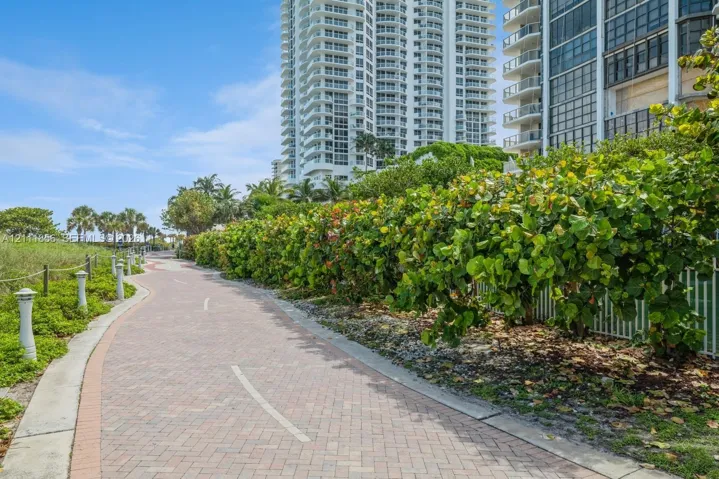 Winding brick-paver pathway bordered by mature tropical vegetation and decorative post lighting