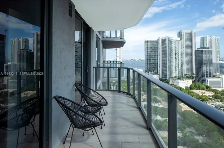 Covered balcony featuring tile flooring and glass panel railings with metal framing