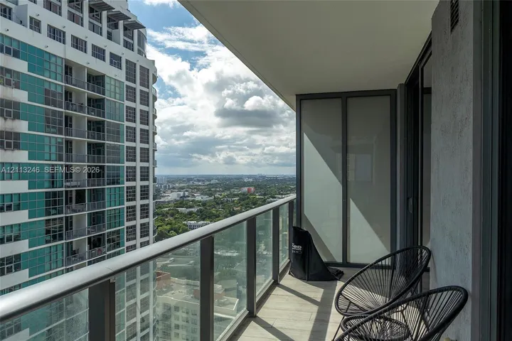 Covered balcony featuring a glass panel railing, tile flooring, and frosted privacy screen