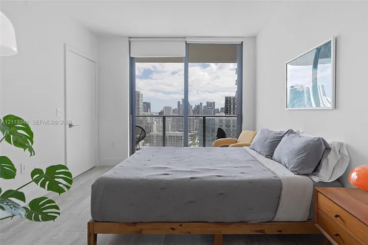 Floor-to-ceiling sliding glass door, private balcony, and light wood-finish flooring