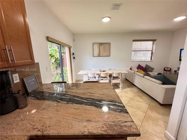 Kitchen featuring stone countertops, natural wood cabinetry, tile flooring, and sliding glass door