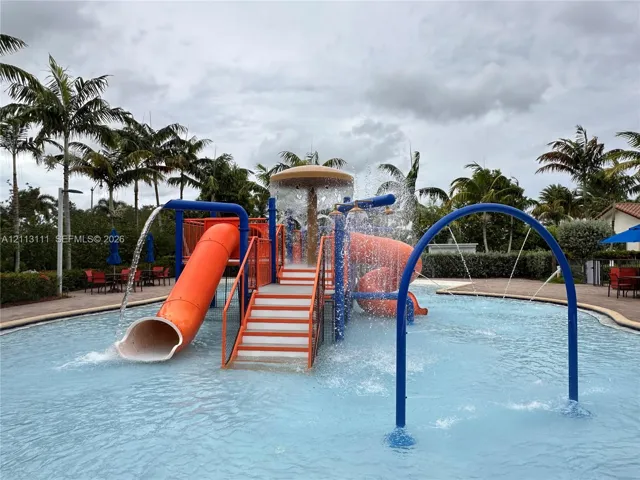 Water recreation area featuring a splash pad, dual slides, integrated overhead shower fountain, and arched water sprayer