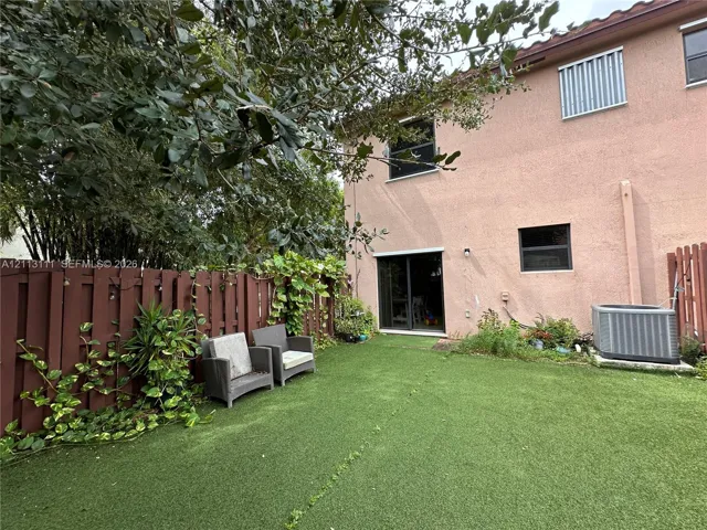 Fenced backyard featuring synthetic turf, stucco exterior siding, and sliding glass door access