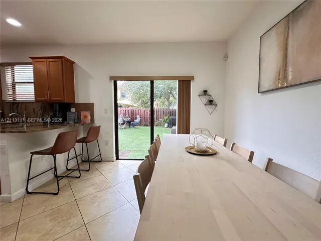 Ceramic tile flooring, stone-finished breakfast bar, recessed lighting, and sliding glass door with integrated vertical blinds