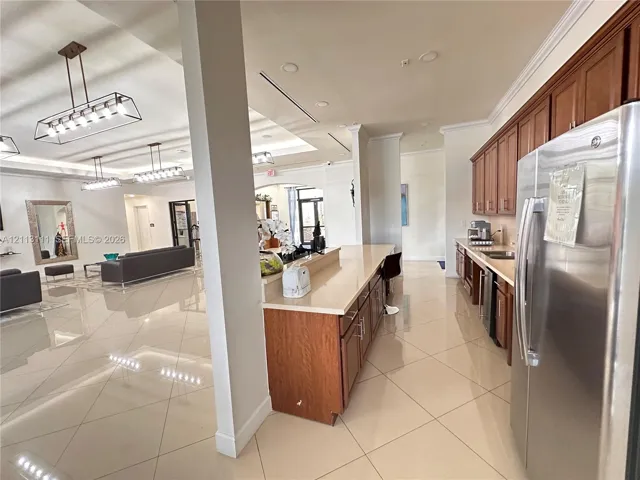 Kitchen featuring wood cabinetry, stone-finish countertops, stainless steel appliances, tile flooring, and multi-light pendant fixtures