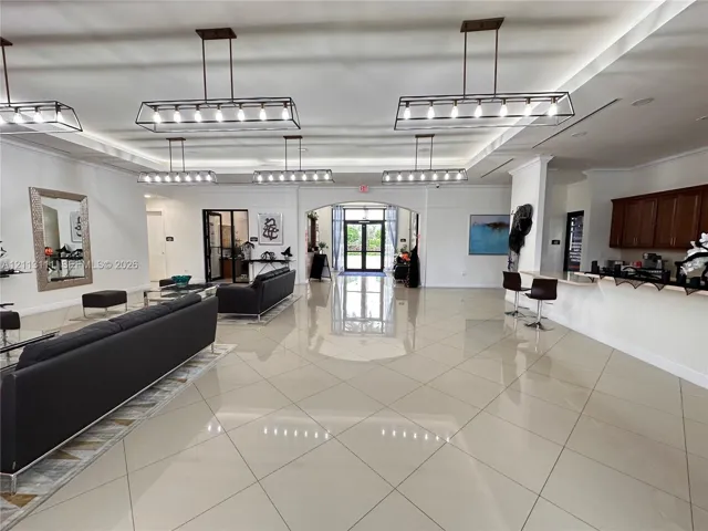 Large interior space featuring high ceilings with recessed lighting, oversized tile flooring, multiple linear pendant light fixtures, and built-in cabinetry