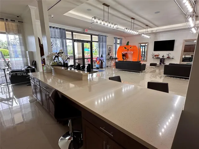 Expansive open-concept space featuring polished tile flooring, recessed tray ceilings, custom linear pendant lighting, and a breakfast bar with stone-finish countertops and built-in​​‌​​​​‌​​‌‌​‌‌​​​‌‌​‌​‌​‌​​​‌​​ cabinetry
